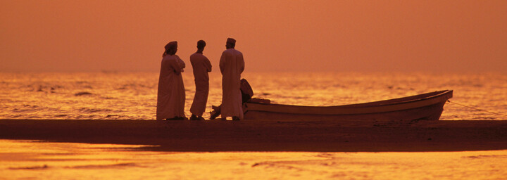 Männer mit Boot im Sonnenuntergang