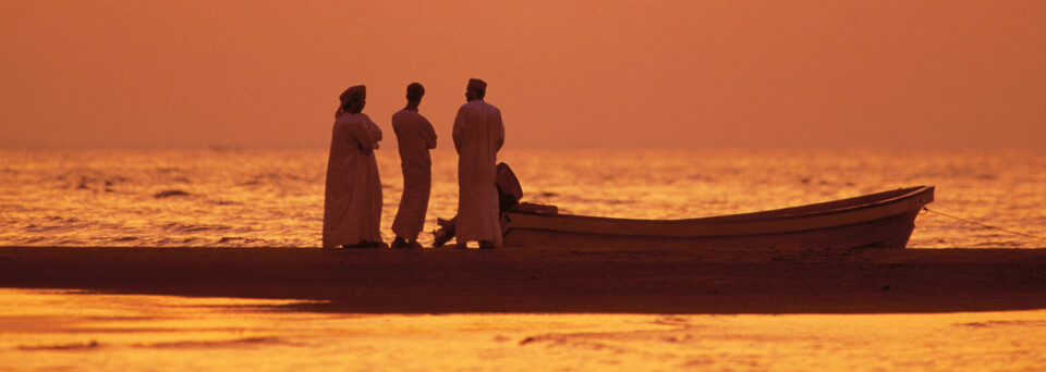 Männer mit Boot im Sonnenuntergang